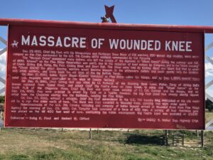 alt="sign with information about the Massacre of Wounded Knee"