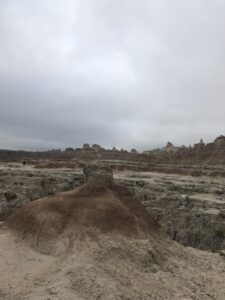 alt="small mound with rocks in background"