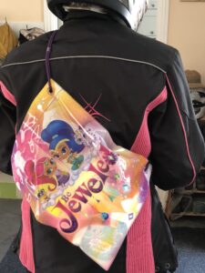 alt="a child's plastic sports back on back of person in motorbike kit"