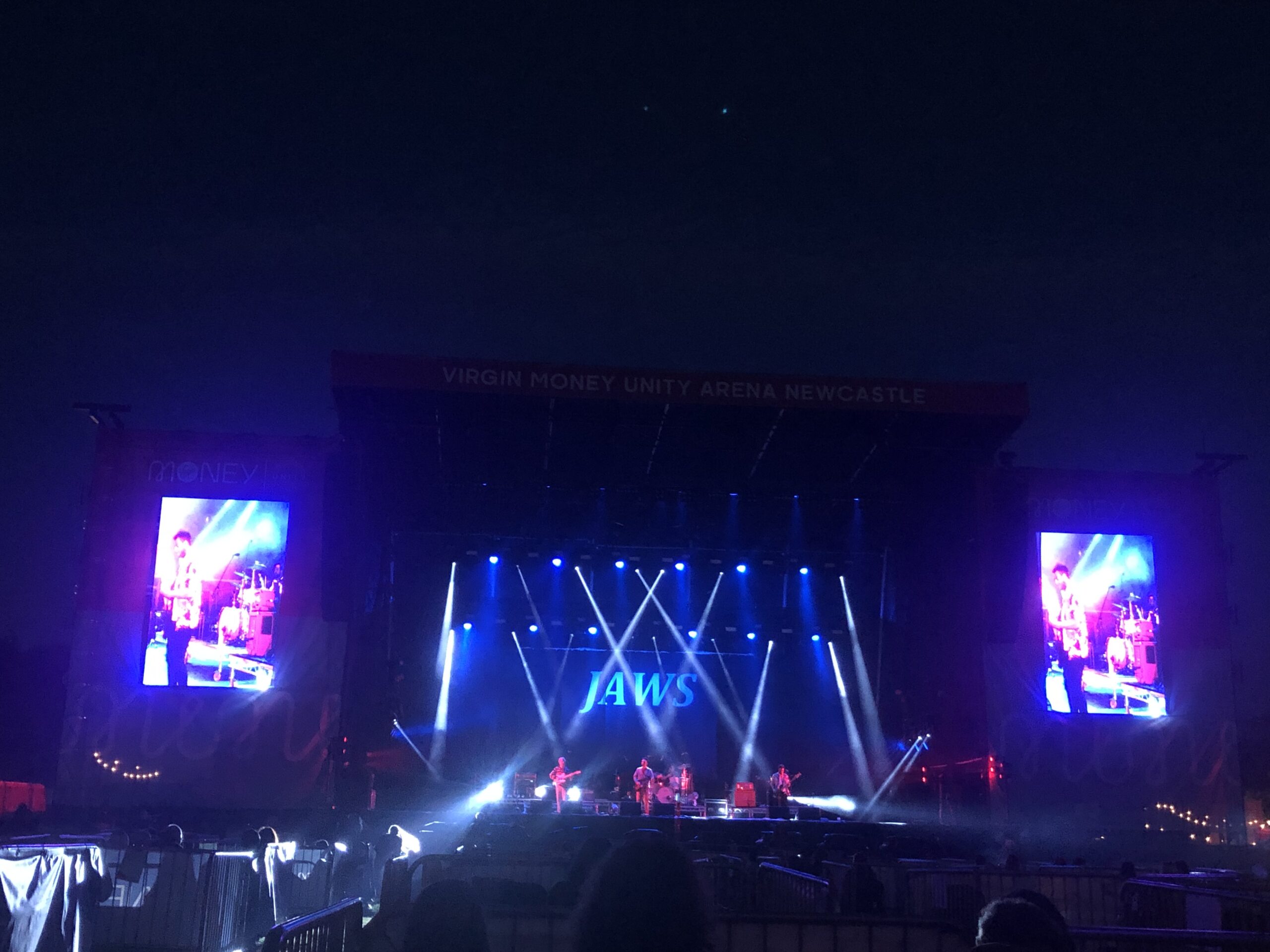 alt="images on screens either side of main stage"