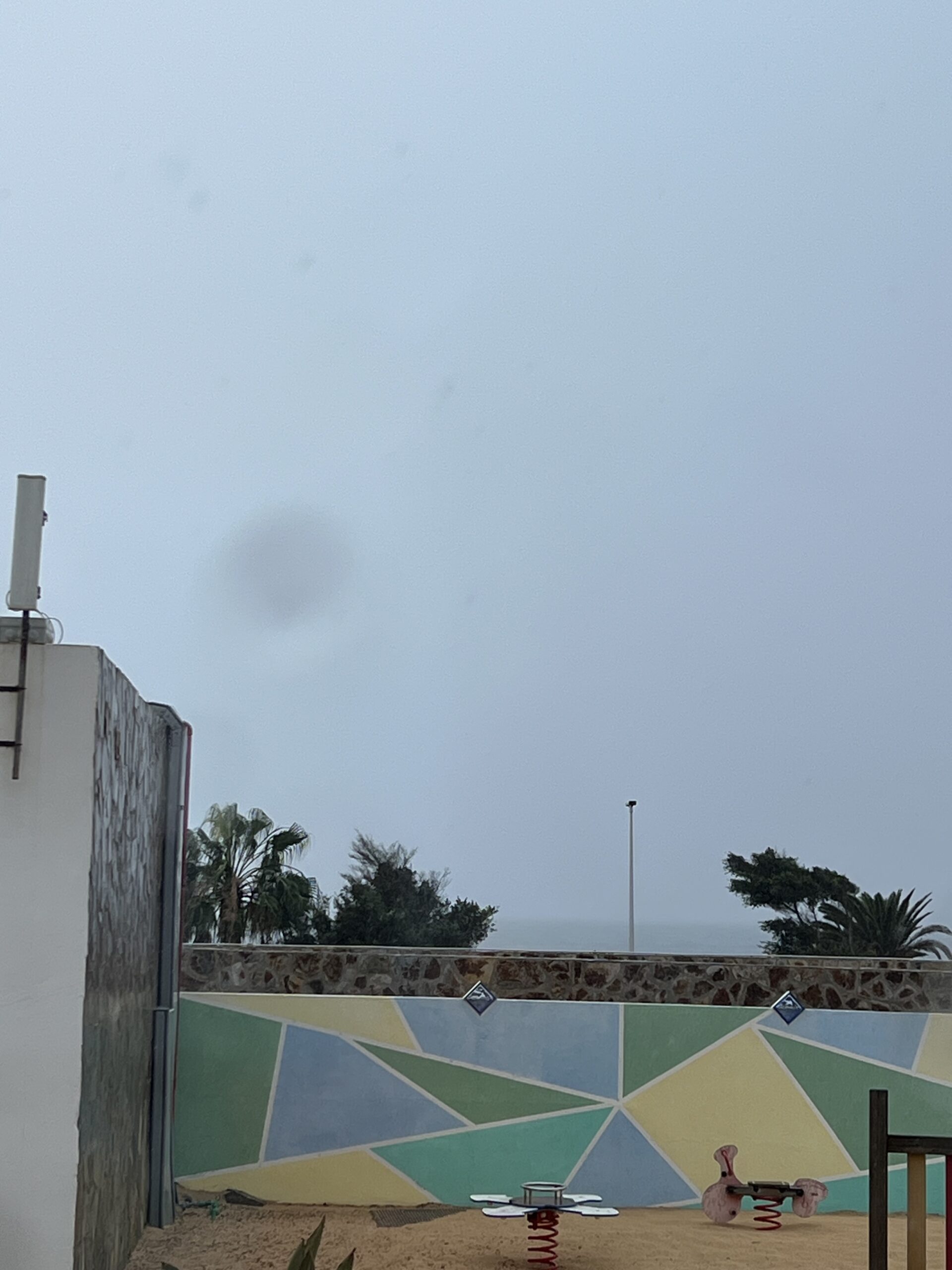 alt="children's play equipment & rainy sky"