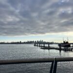 alt="water & boat moorings with clouds above"